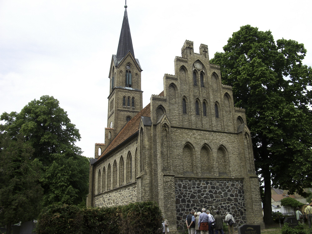 Eine Gruppe Menschen sehen vor der Kirche in Glindow.